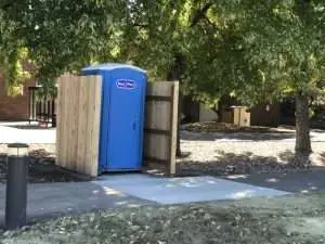 porta-potty with wood fencing around three sides